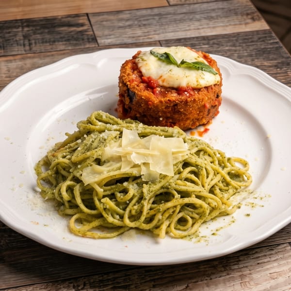 Pesto spaghetti with parmesan and a breaded dish topped with melted mozzarella and basil.