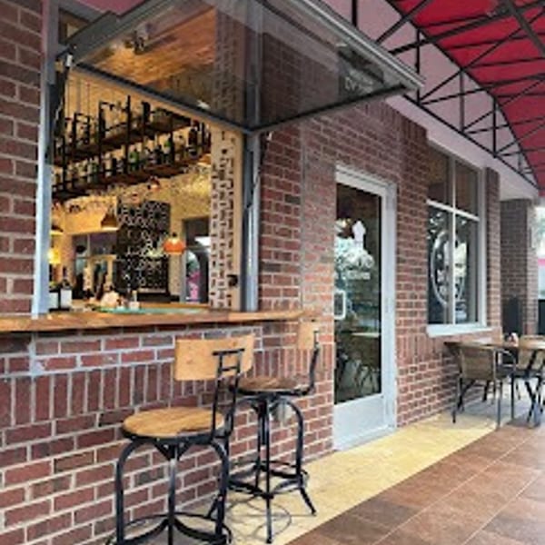 Outdoor bar seating with two stools at a brick restaurant under a red awning.